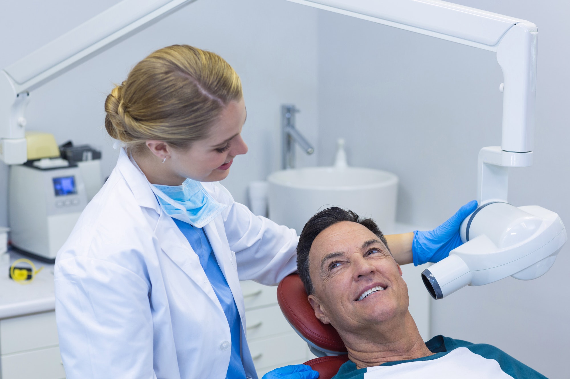 Dentist examining a male patient with dental tool