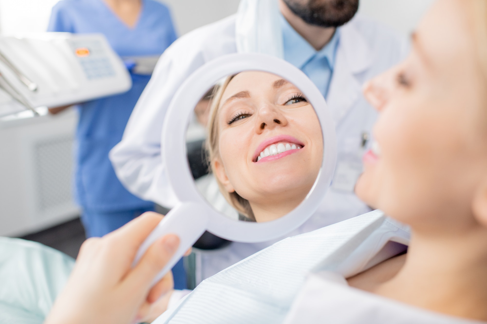 Reflection in mirror of healthy smile of pretty young smiling female patient